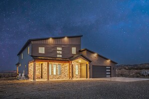 A two-story house with a stone facade, a garage, and a covered patio area. - The Cliffs - Bryce Canyon-Zion- Hot Tub- Family Home Sleeps 10 (Hatch)