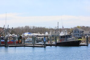 A marina with boats docked, a pilot boat, and a house in the background. - Beachland H (East Sandwich)