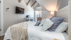 Ein Schlafzimmer mit einem Bett, einem an der Wand montierten Fernseher und einer Treppe, die zu einer oberen Ebene führt.