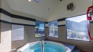 Ein Whirlpool mit Metallgeländer, einem roten Telefon und einem Fenster mit Blick auf die Berge.