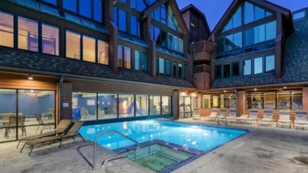Ein modernes Gebäude mit Pool, großen Fenstern und Außenbereichen mit Sitzmöglichkeiten.