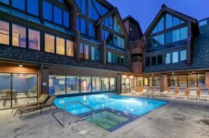 Un edificio moderno con piscina, ventanas amplias y zonas de estar al aire libre.
