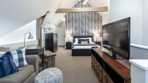 A modern bedroom with a large bed, a TV, a desk, and a ceiling light fixture.