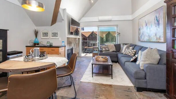 A spacious living area with a dining table, a sofa, and a fireplace.