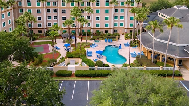 Un hotel con piscina, palmeras y vistas a la ciudad.