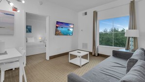 Una habitación de hotel moderna con una cama, un escritorio, un televisor, un sofá y un ventanal con vistas.