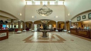 Un vestíbulo amplio con una fuente central, un mostrador de recepción y un espacio de atención al cliente.