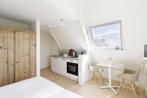A modern kitchen with a dining area, wooden wardrobe, and a large window. - Villa Parnassia (Bergen aan Zee)