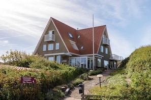 A two-story building with a sloped roof, multiple windows, and a balcony. - Villa Parnassia (Bergen aan Zee)
