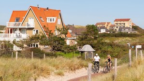 A coastal residential area with houses featuring red-tiled roofs and white balconies. - Villa Parnassia (Bergen aan Zee)