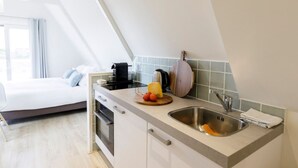 A compact kitchen with a built-in oven, a sink, and a countertop with a cutting board and tomatoes. - Villa Parnassia (Bergen aan Zee)
