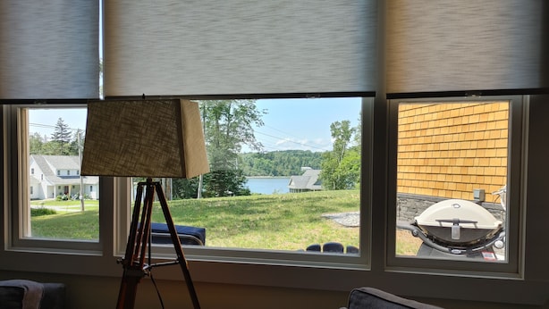 A room with a large window, a tripod with an easel, a remote control, and a grill outside.