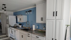 A modern kitchen with white cabinets, a granite countertop, and a blue accent wall.