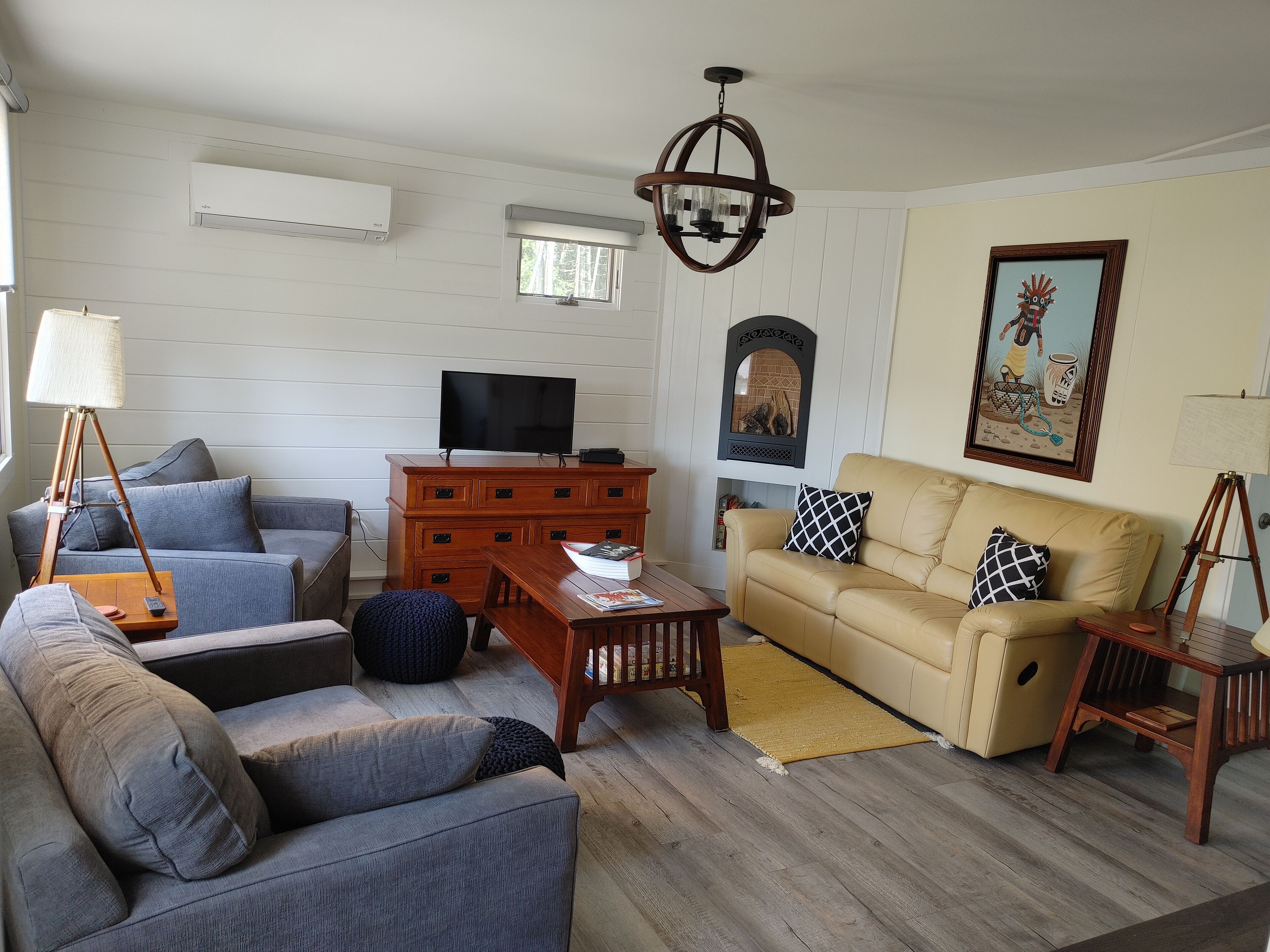 A living room with a sofa, a coffee table, a TV on a wooden cabinet, a lamp, and a painting on the wall.