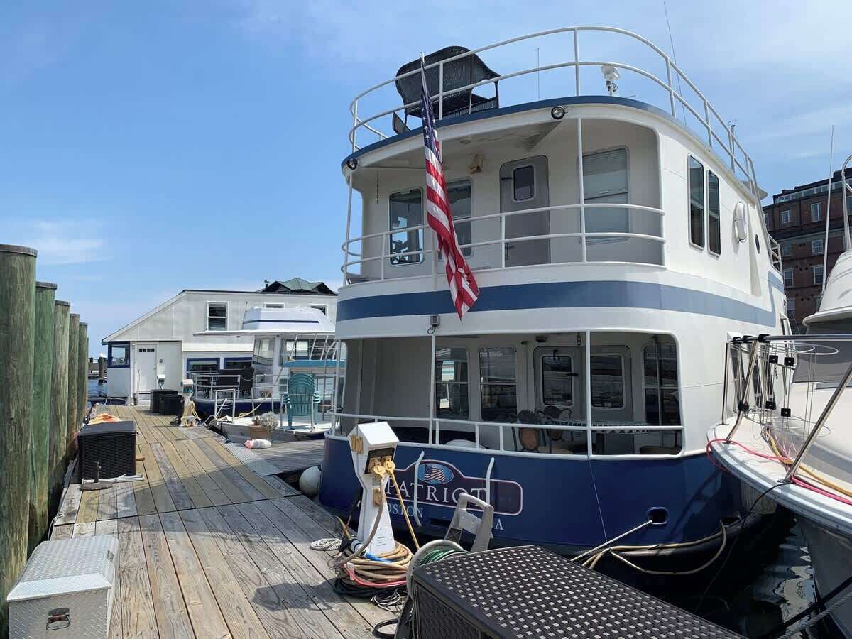 A docked boat with a cabin, a flag, and a wooden deck.