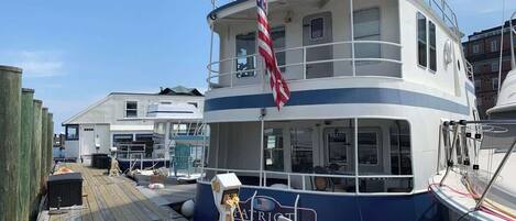 A docked boat with a cabin, a flag, and a wooden deck.