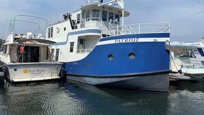 A blue and white boat named 'Patriot' docked at a marina.