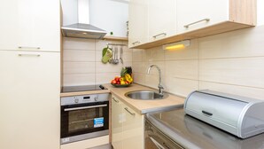 A modern kitchen with white cabinets, a stainless steel sink, a built-in oven, and a toaster.