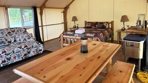 A tented accommodation with a bed, a table with a blender, and a sofa with patterned bedding. - Howling Wolf Resort!  (Seward)