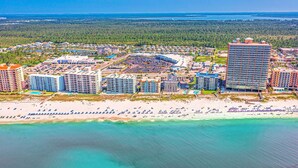 An aerial view of a coastal resort area with multiple high-rise hotels, a sandy beach, and a clear view of the ocean. - New Beautiful 3bed/2bath Beachfront Condo! (Orange Beach)