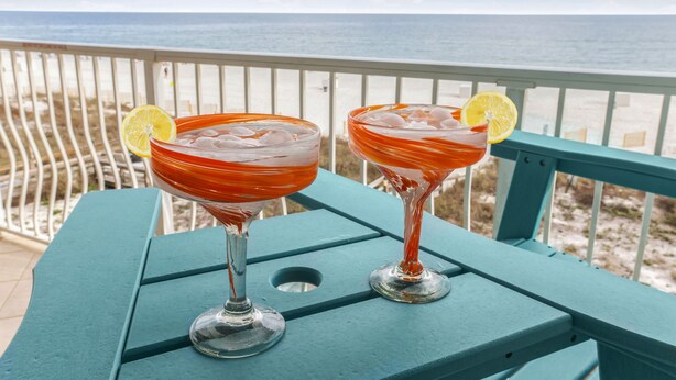 Two cocktails on a teal table with a view of the beach and ocean. - New Beautiful 3bed/2bath Beachfront Condo! (Orange Beach)