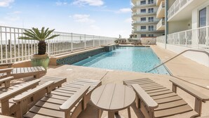 A rooftop pool area with lounge chairs and a palm tree. - New Beautiful 3bed/2bath Beachfront Condo! (Orange Beach)