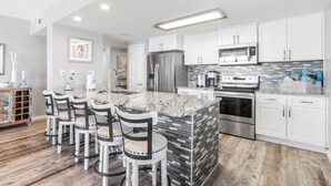 A modern kitchen with white cabinets, a marble island, and stainless steel appliances. - New Beautiful 3bed/2bath Beachfront Condo! (Orange Beach)