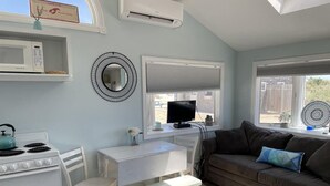 A compact living space with a kitchenette, a dining area, a seating area, and a window providing a view of the outside.