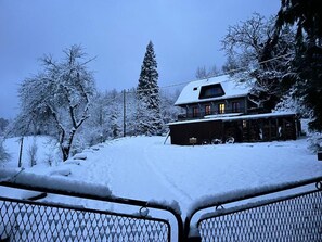 Situated in a serene mountainous area, this cozy cabin offers a balcony overlooking snow-covered trees.