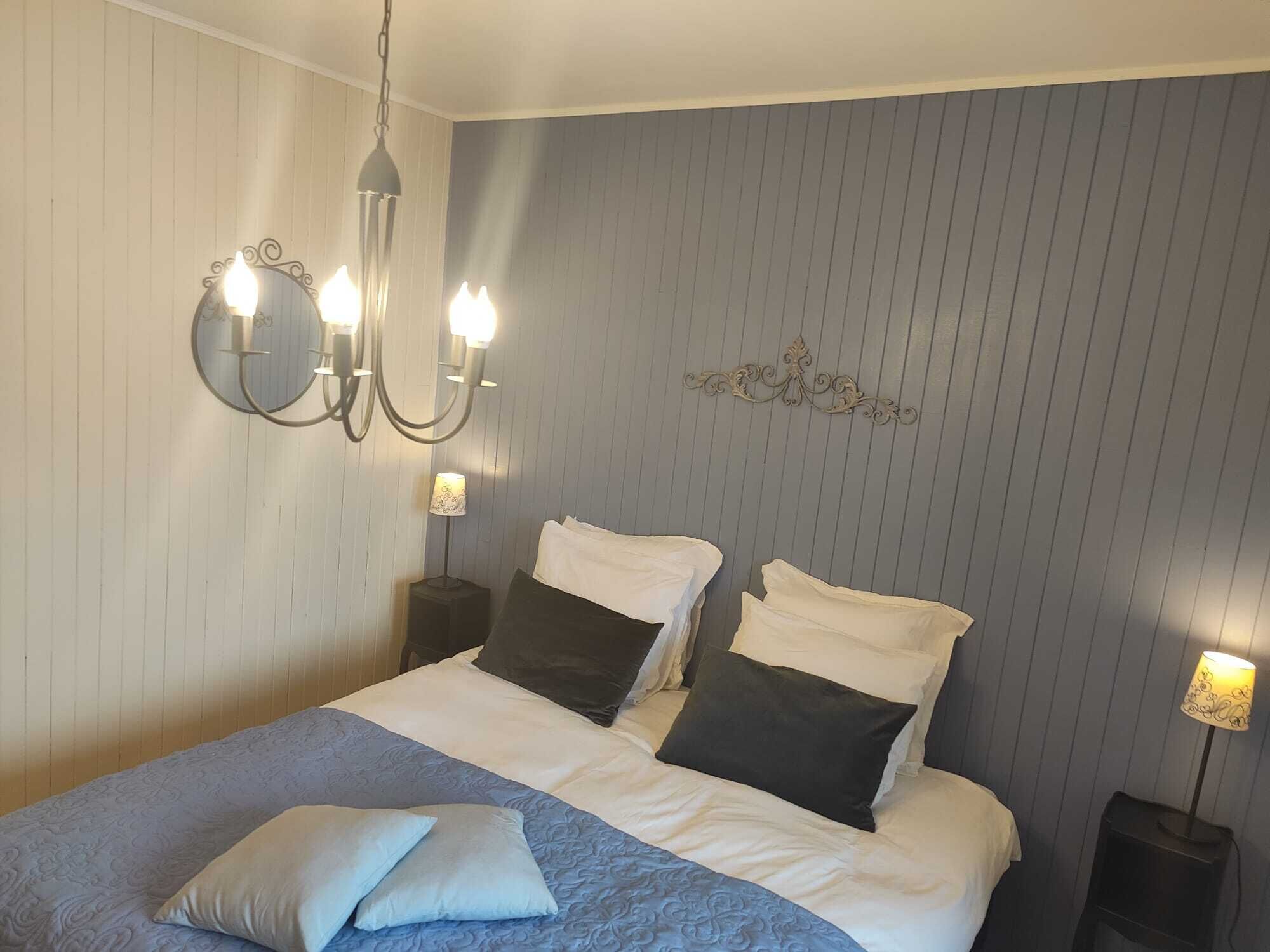 Ein Schlafzimmer mit einem Bett, zwei Nachttischen, einer Wandleuchte und einer Wanddekoration.
