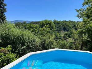 Relax by the serene pool surrounded by lush greenery and rolling hills.