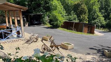 A rustic outdoor area with a wooden structure, a cart, and a gravel path.