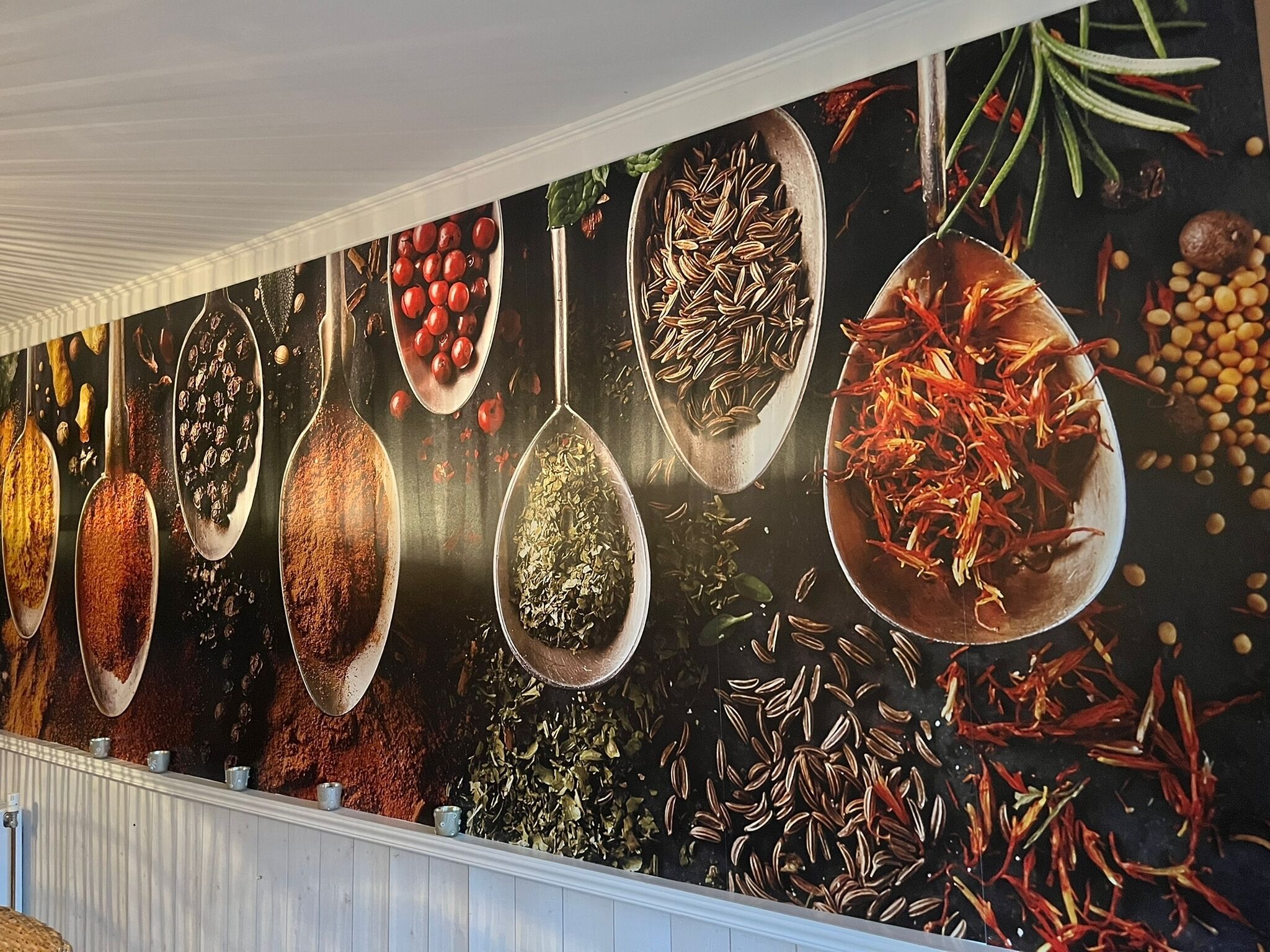 Eine Wand mit verschiedenen Gewürzen, die in Löffeln präsentiert werden.