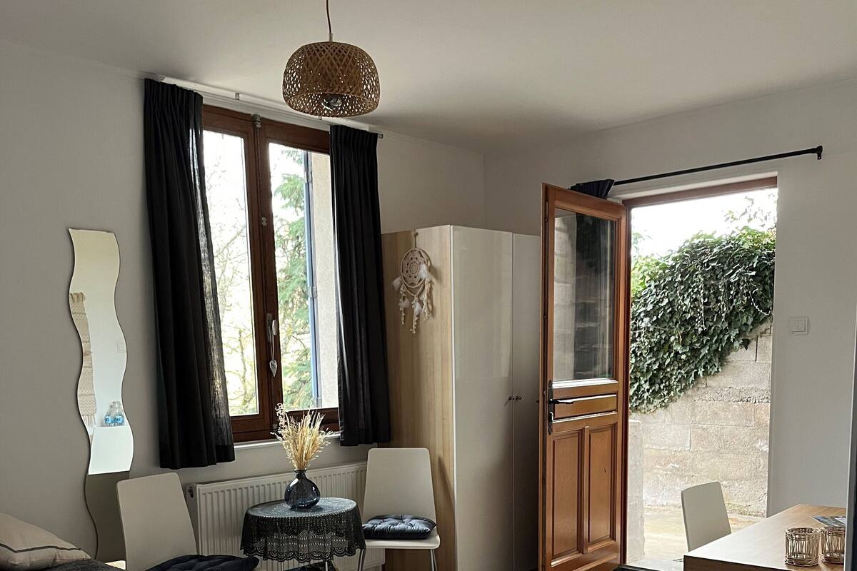 A bedroom with a bed, a desk, a chair, a wardrobe, and a window with curtains.