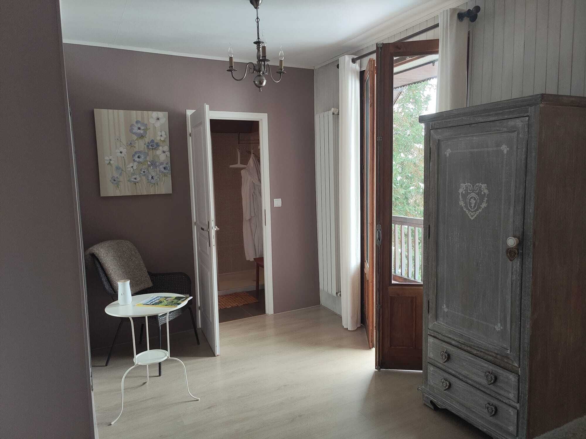 Una habitación con un armario de madera, una silla, una mesa y un cuadro en la pared.