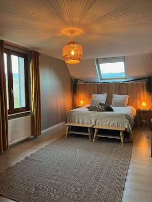 Cozy retreat with a large bed, bedside tables, and a bench, offering a peaceful view from the window.