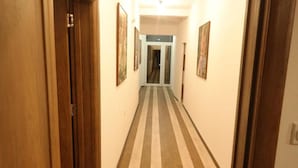 Ein Korridor mit Streifenboden, Holztüren und gerahmten Kunstwerken an den Wänden.