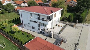 Ein mehrstöckiges Gebäude mit rotem Dach, umgeben von Grünflächen und anderen Wohnhäusern.