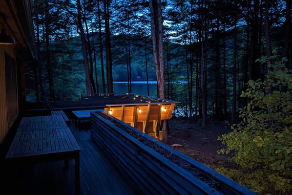 A wooden deck with a built-in seating area overlooking a forested area and a body of water.