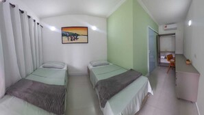 A room with two beds, a desk, a chair, and a painting on the wall.