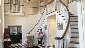 Un magnifique escalier avec des balustrades blanches et une moquette noire et dorée menant à un palier.