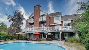Une maison à deux étages avec une piscine, un patio couvert et une cour arrière clôturée.