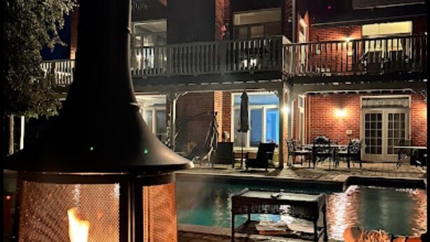Un espace extérieur aménagé avec une piscine, du mobilier de jardin et une grande cheminée.