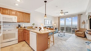A modern kitchen with wooden cabinets, a central island, and a dining area with a view.