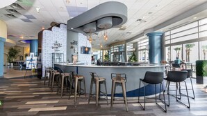 Zona de bar moderna con una barra curva, varios taburetes y un muro con diseño.