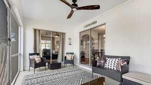 A spacious patio with a ceiling fan, a patterned rug, and wicker furniture. - Heated Pool + Game Room | Near Vanderbilt Beach (Naples)
