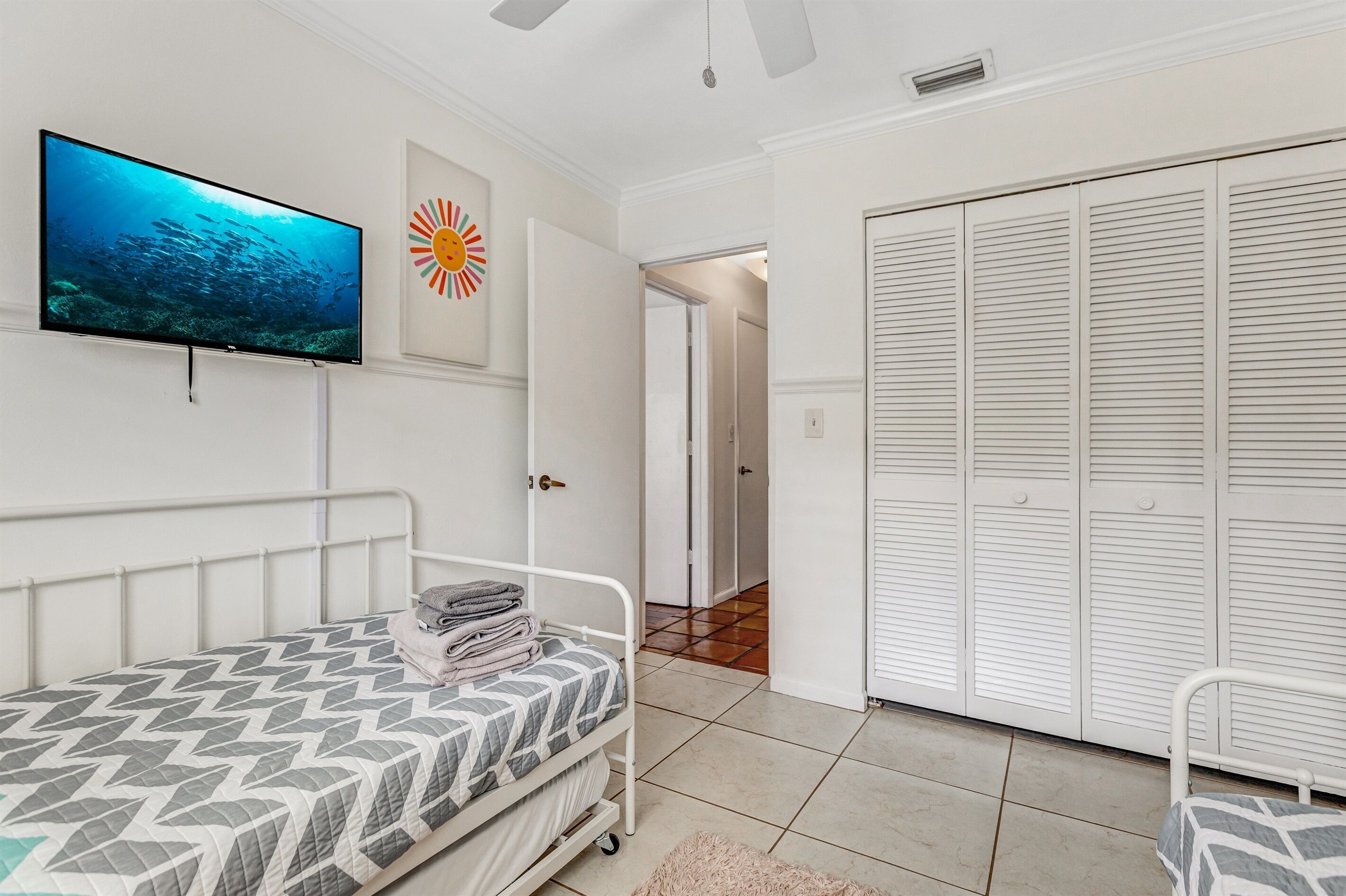 A bedroom with a bed, a television, a wardrobe, and a door leading to another room.