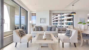 A modern living room with a sofa, two armchairs, a coffee table, and a dining area with chairs and a table.