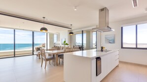 A modern kitchen with a large island, white cabinetry, and a view of the ocean.