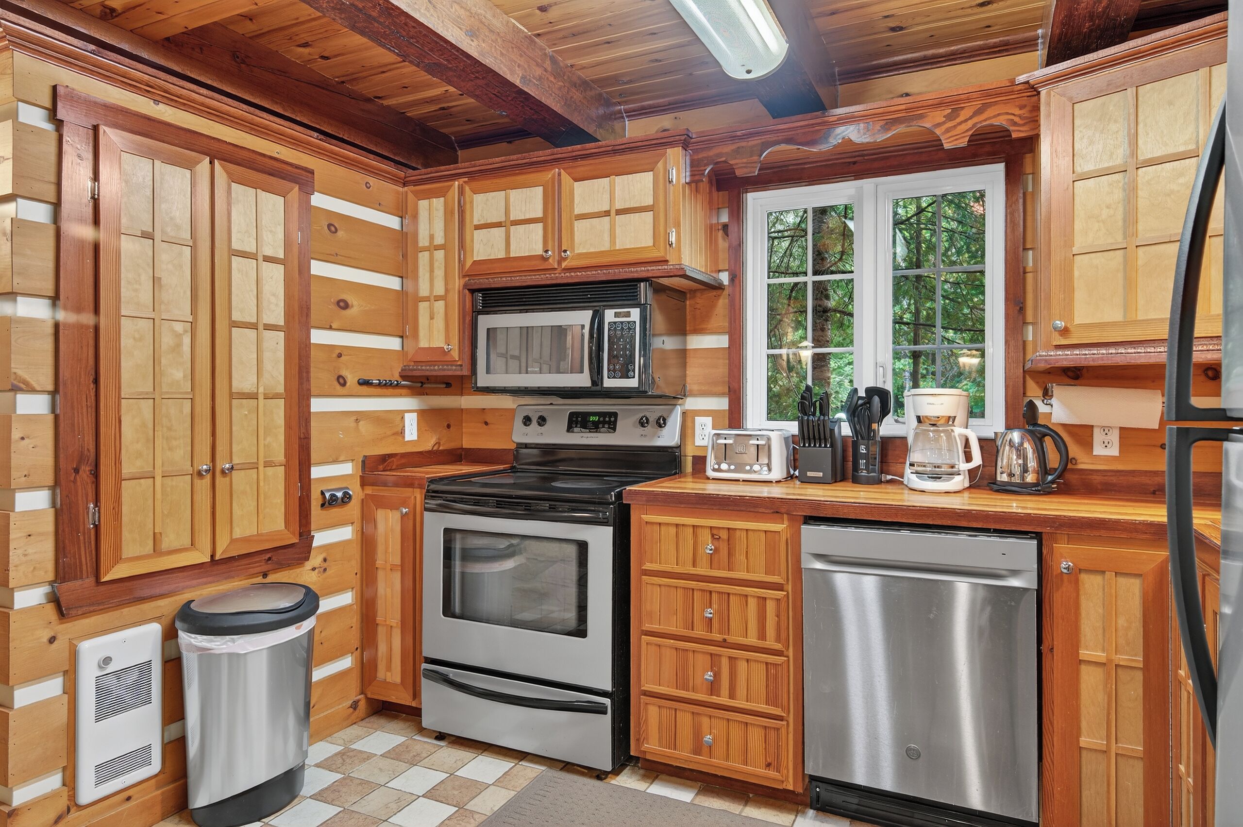 A kitchen with wooden cabinets, a microwave, stove, toaster, and dishwasher.